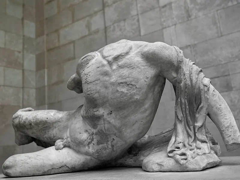 Ancient Greek statue of a reclining male figure with missing head and arms
