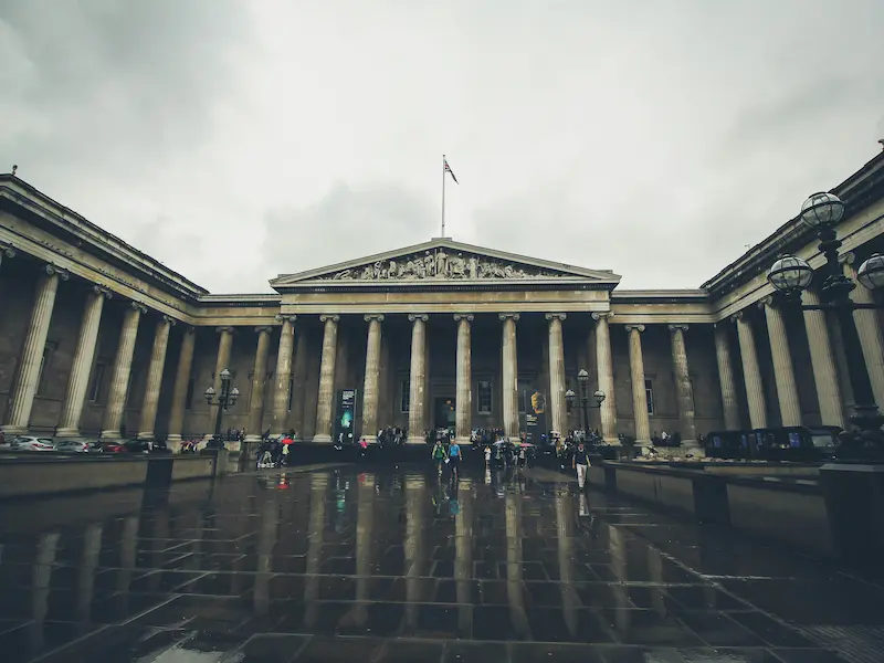 The grand neoclassical facade of the British Museum in London on a cloudy day