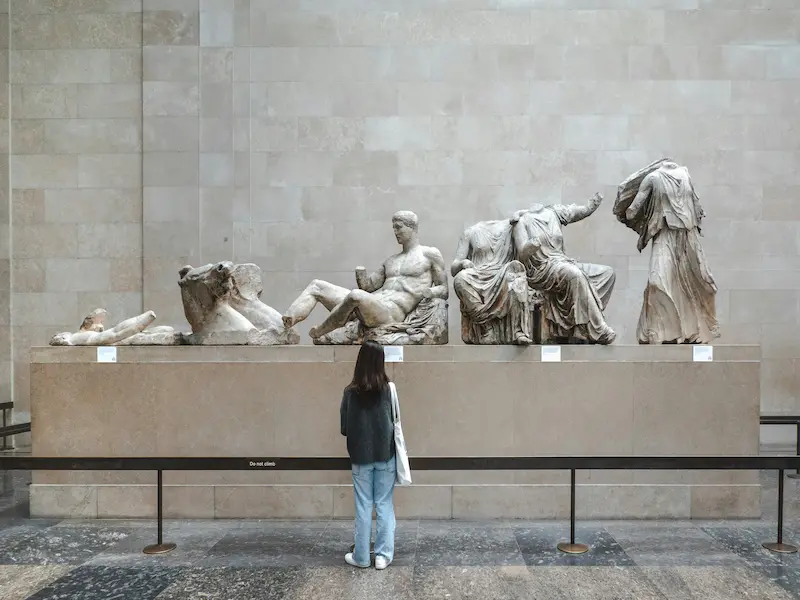 A visitor admiring the Parthenon Marbles, an ancient Greek sculpture collection, at the British Museum.