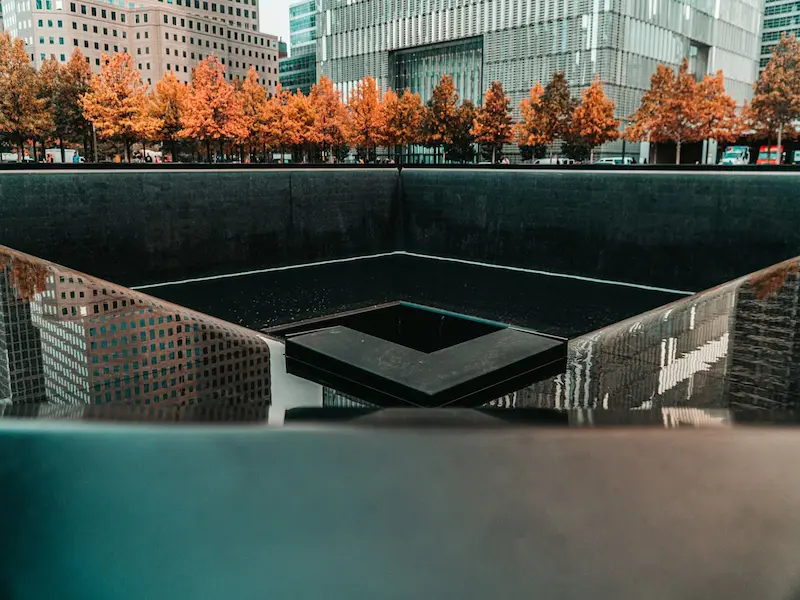 The 9/11 Memorial reflecting pool surrounded by autumn trees