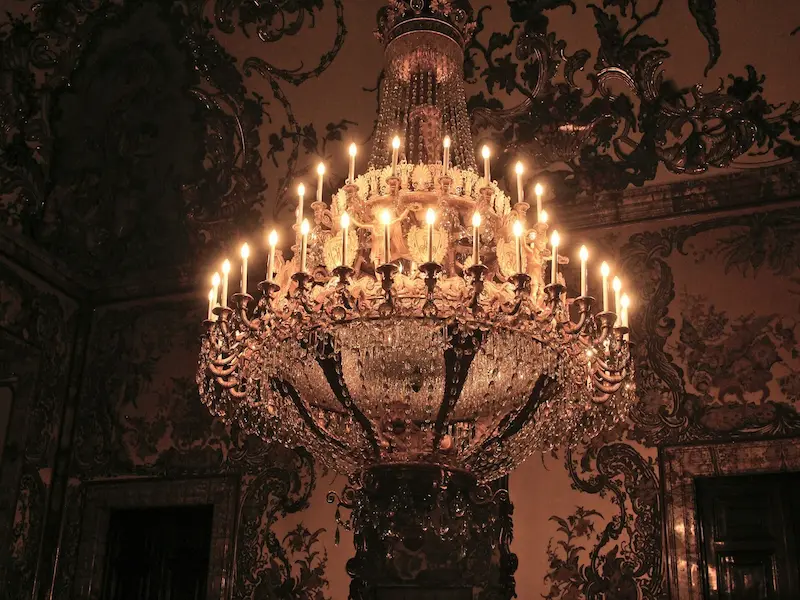 a chandelier with many lit candles hanging inside royal palace of madrid