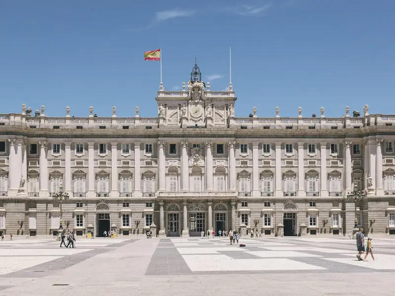 a large building with coloums and flag on top on the royal palace of madrid
