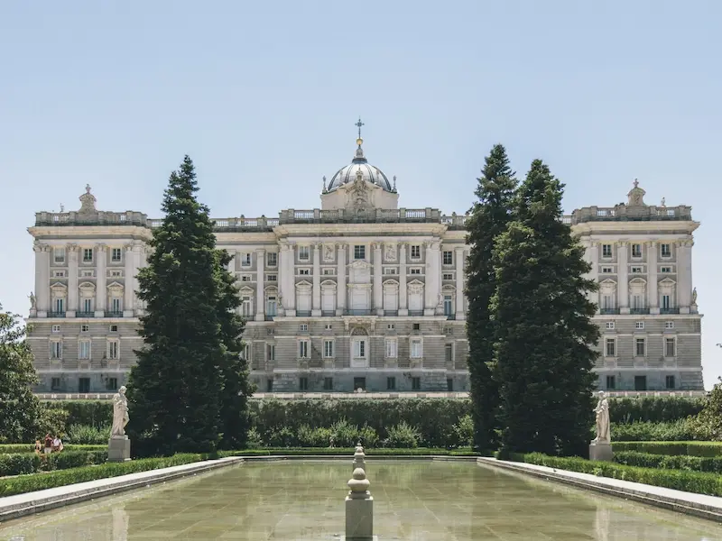 large building with trees infront of royal palace of madrid