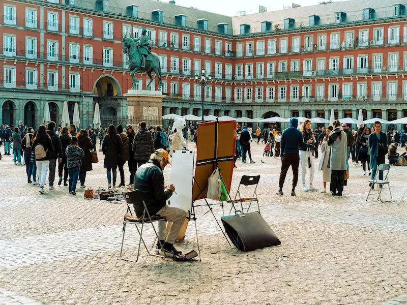 people walking and man sitting in front of plaza mayor madrid spain