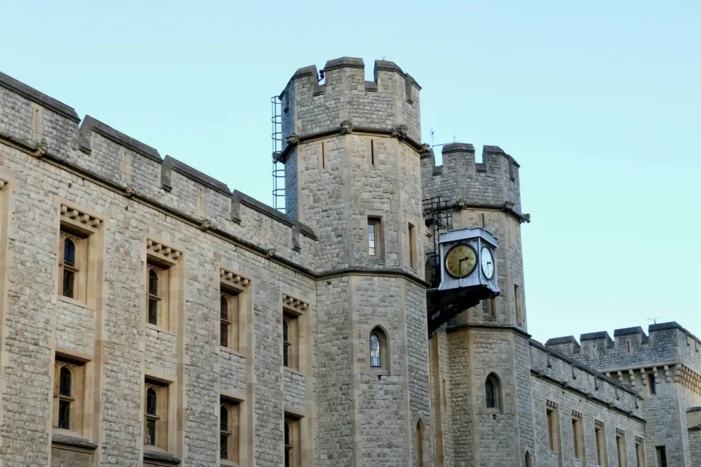 A detailed view of a clock tower on the Tower of London’s stone structure.